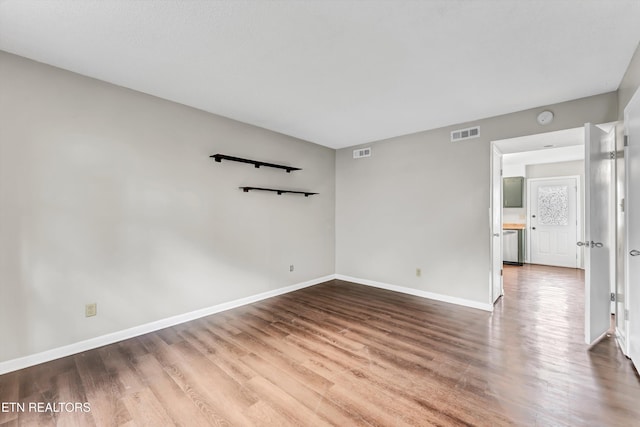 unfurnished room with visible vents, baseboards, and wood finished floors