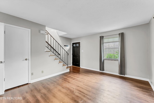 entryway featuring stairway, baseboards, and wood finished floors