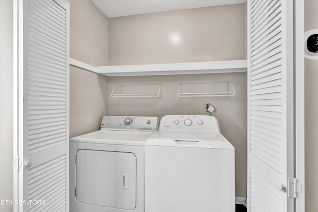 laundry area with laundry area, washing machine and clothes dryer, and a textured ceiling