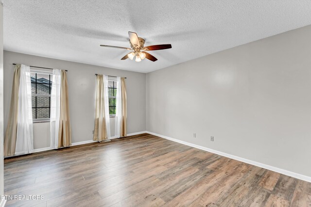 unfurnished room featuring a textured ceiling, baseboards, a ceiling fan, and wood finished floors