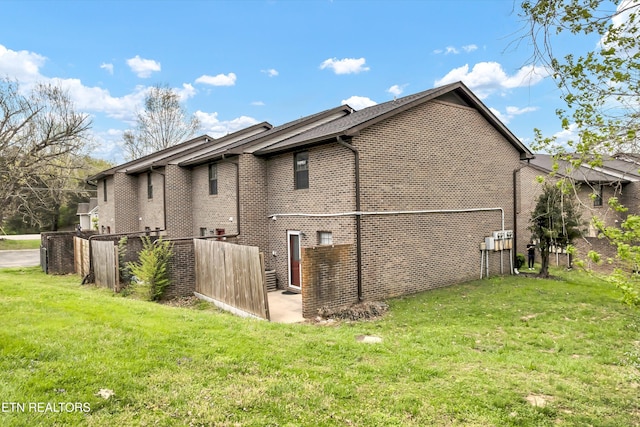 view of side of property featuring brick siding and a lawn