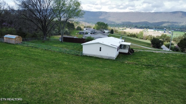 view of storm shelter featuring an outdoor structure, a mountain view, fence, and a yard