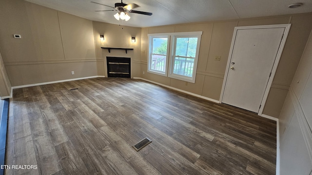 unfurnished living room featuring wood finished floors, ceiling fan, a decorative wall, and a glass covered fireplace