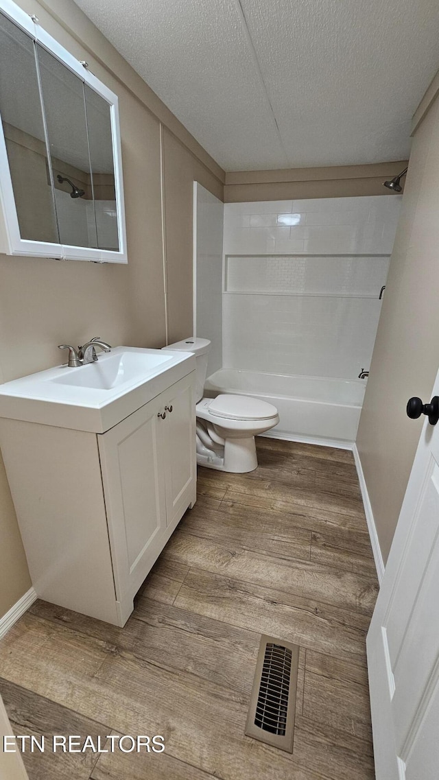full bathroom featuring toilet, vanity, wood finished floors, washtub / shower combination, and visible vents