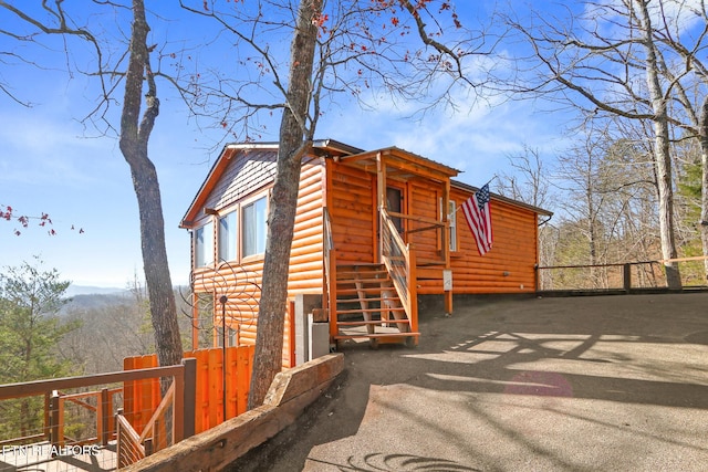 view of front facade with faux log siding and fence