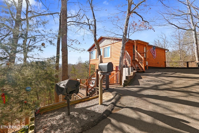 view of home's exterior with faux log siding and aphalt driveway
