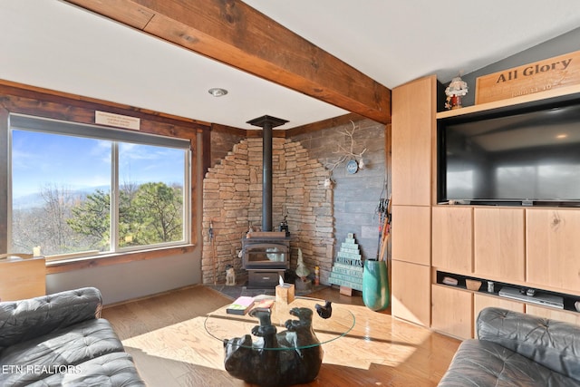 living area featuring wood finished floors, a wood stove, and beamed ceiling