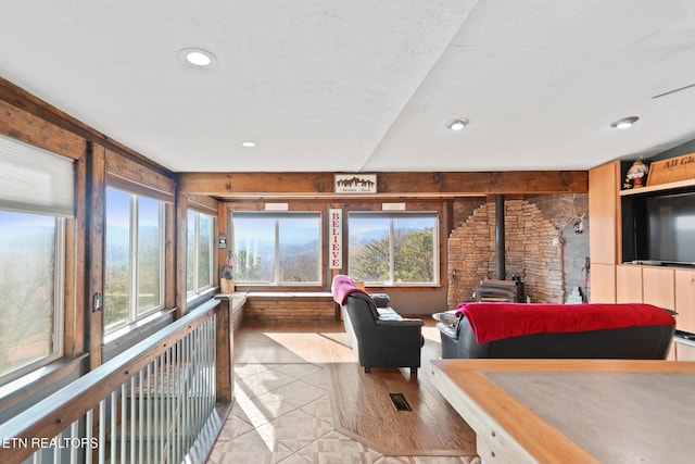 sunroom / solarium featuring visible vents, a wood stove, recessed lighting, and tile patterned flooring
