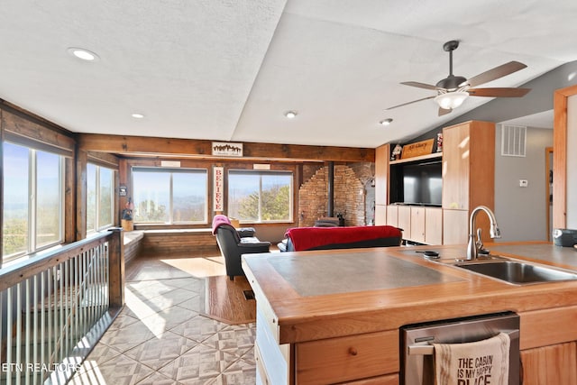kitchen featuring visible vents, a ceiling fan, a sink, open floor plan, and a wood stove