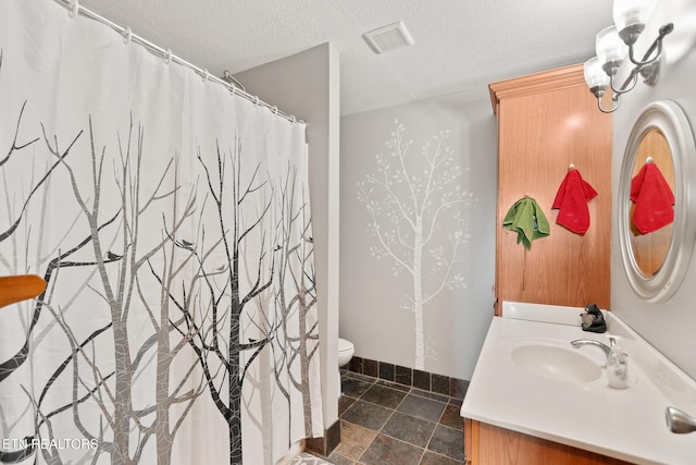 full bathroom featuring toilet, vanity, baseboards, and a textured ceiling