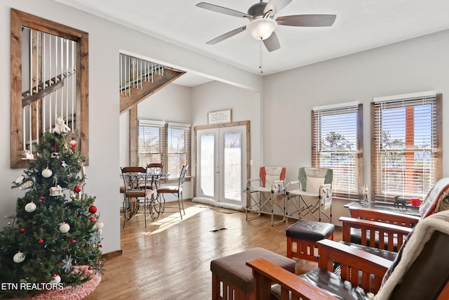 interior space with plenty of natural light, wood finished floors, ceiling fan, and french doors