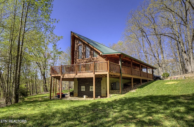 rear view of property featuring log exterior, a deck, metal roof, and a lawn