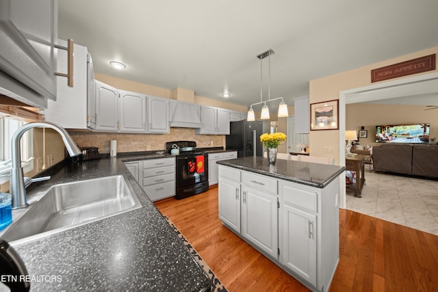 12 Wessex Ct, Crossville, TN 38558 - kitchen featuring light wood finished floors, a sink, custom range hood, black appliances, and a center island