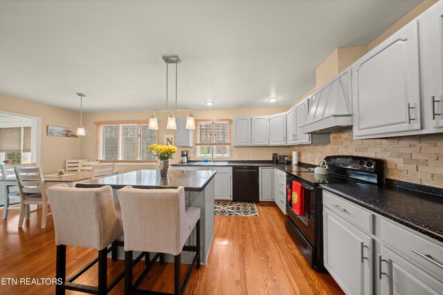 12 Wessex Ct, Crossville, TN 38558 - kitchen featuring white cabinets, premium range hood, light wood-type flooring, black appliances, and a kitchen breakfast bar