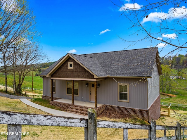 view of front of property featuring covered porch, a shingled roof, and brick siding