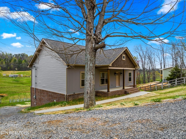 view of front of house with covered porch, fence, and roof with shingles