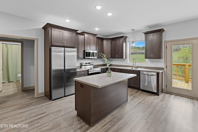 kitchen featuring light wood finished floors, a sink, stainless steel appliances, and dark brown cabinetry