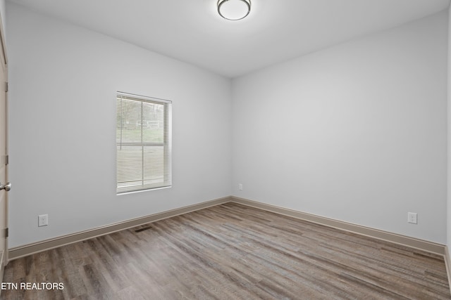 unfurnished room with baseboards, visible vents, and wood finished floors