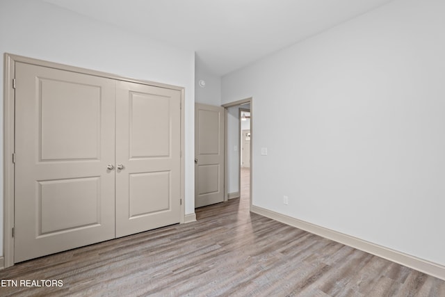 unfurnished bedroom featuring a closet, baseboards, and wood finished floors