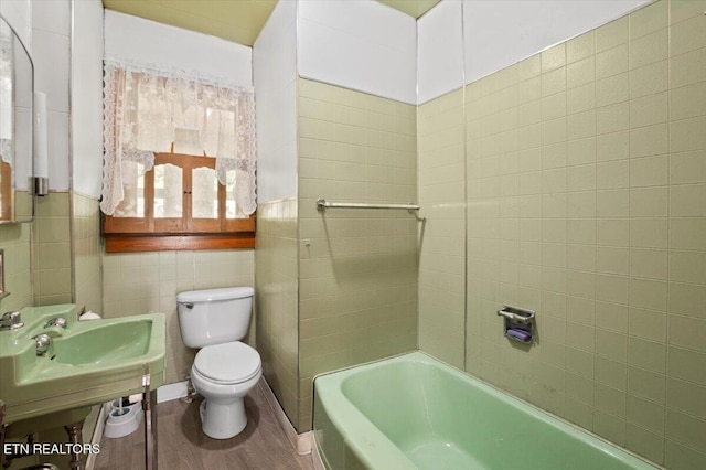 bathroom featuring tile walls, toilet, and wood finished floors