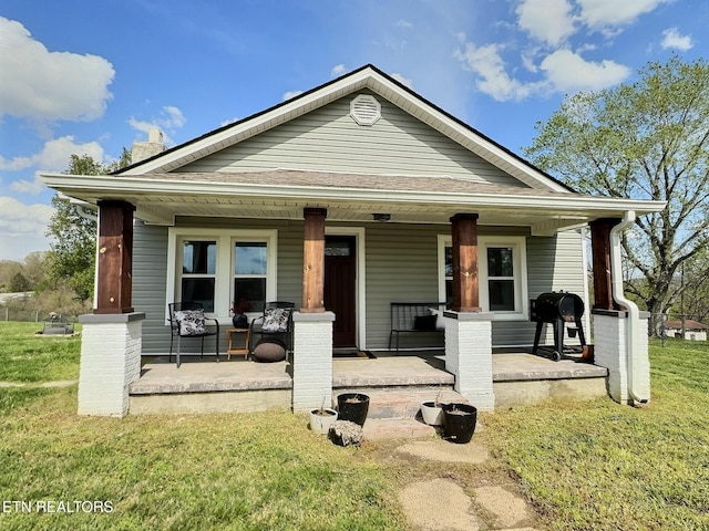 bungalow-style home with covered porch and a front lawn