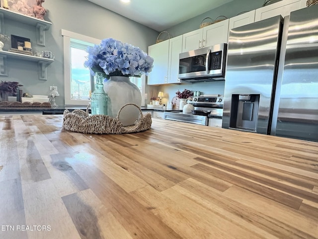kitchen with white cabinets, wood finished floors, and appliances with stainless steel finishes