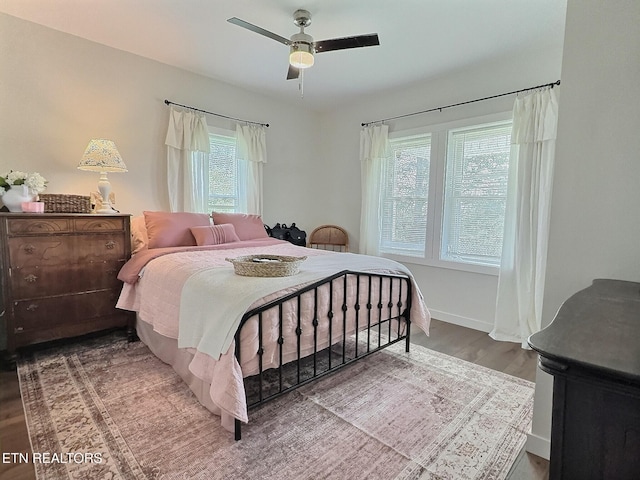 bedroom featuring baseboards, wood finished floors, and ceiling fan
