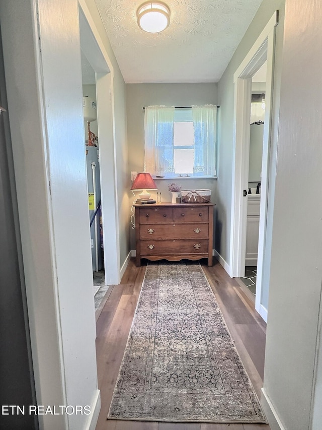 bathroom featuring water heater, baseboards, a textured ceiling, and wood finished floors