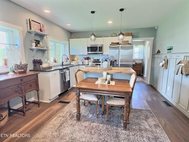 kitchen featuring a sink, appliances with stainless steel finishes, dark wood finished floors, dark countertops, and visible vents