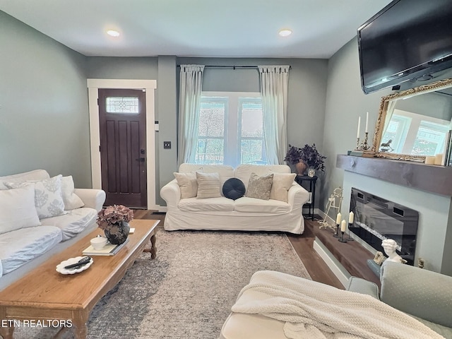 living room featuring baseboards, recessed lighting, wood finished floors, and a glass covered fireplace