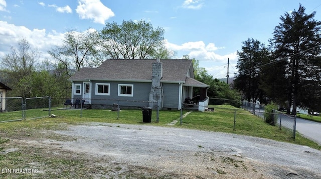 view of front of house featuring a front lawn, a shingled roof, a gate, and fence private yard