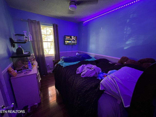 bedroom with wood finished floors, ceiling fan, and a textured ceiling