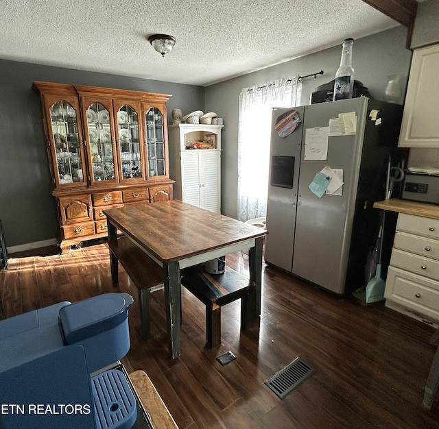 dining room with dark wood-type flooring, a textured ceiling, and visible vents