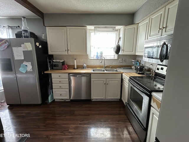kitchen with light countertops, a sink, tasteful backsplash, appliances with stainless steel finishes, and dark wood finished floors