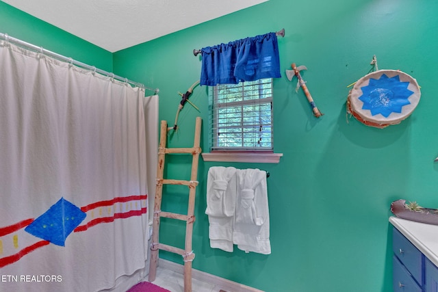 bathroom featuring vanity, baseboards, and curtained shower