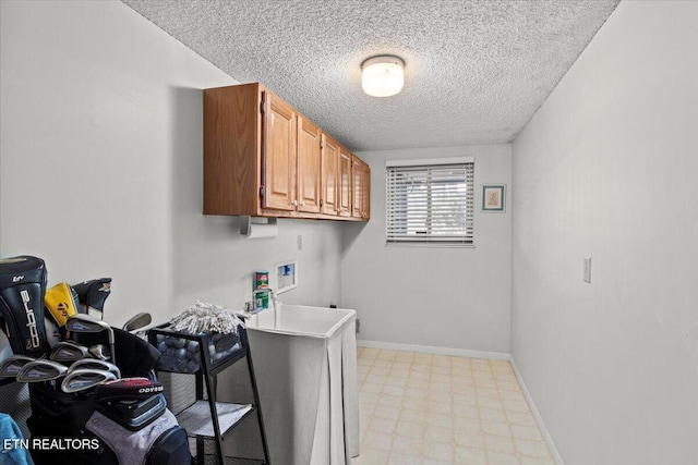 clothes washing area with baseboards, a textured ceiling, cabinet space, hookup for a washing machine, and light floors