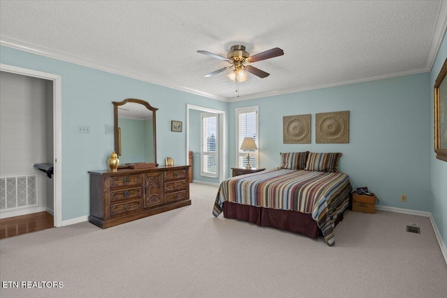 bedroom with baseboards, a textured ceiling, crown molding, visible vents, and carpet