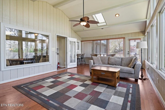 sunroom with vaulted ceiling with skylight and wood finished floors