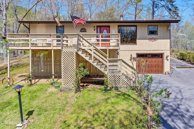 view of front facade featuring aphalt driveway, a wooden deck, stairway, a front lawn, and an attached garage
