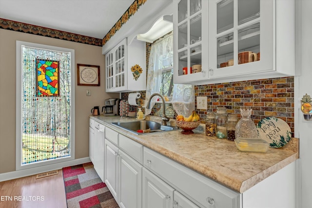 kitchen featuring visible vents, baseboards, a sink, light countertops, and backsplash