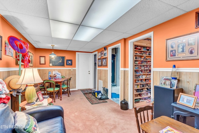playroom featuring wood walls, carpet, wainscoting, and a drop ceiling