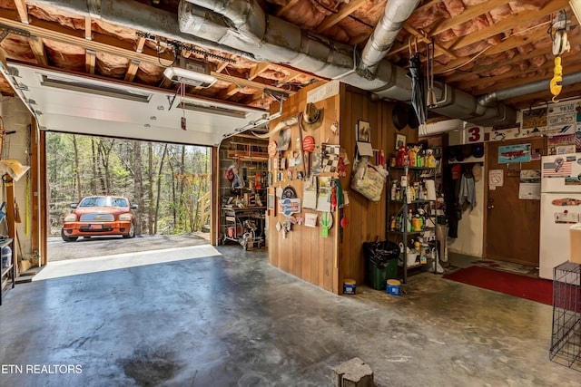 garage featuring a garage door opener and wooden walls