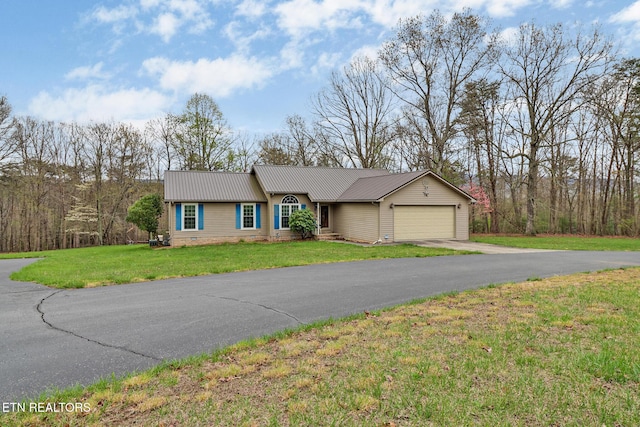 ranch-style house featuring a front yard, an attached garage, metal roof, and aphalt driveway