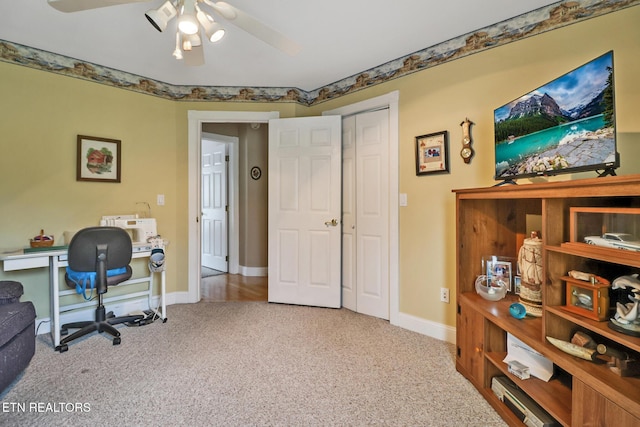 carpeted office with ceiling fan and baseboards