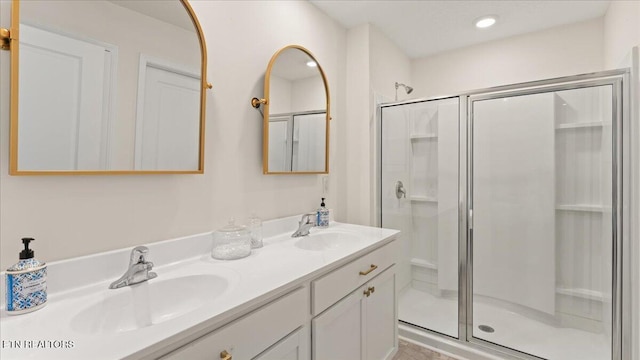 full bathroom with a stall shower, double vanity, and a sink