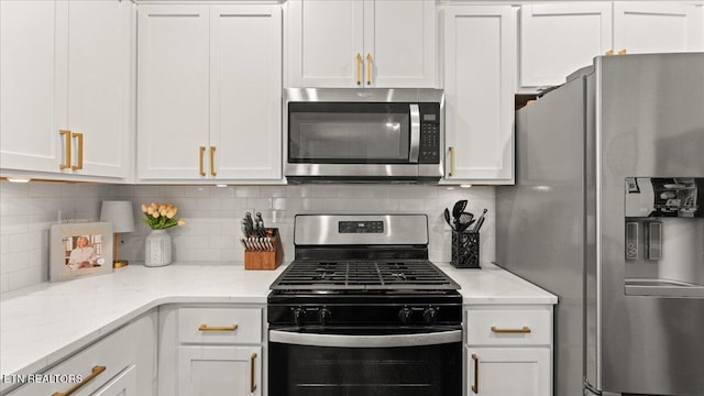 kitchen featuring tasteful backsplash, light stone countertops, white cabinetry, and appliances with stainless steel finishes