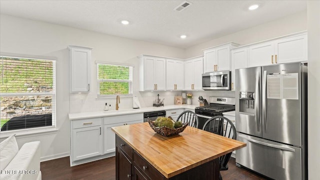kitchen with butcher block countertops, dark wood-style flooring, white cabinetry, visible vents, and appliances with stainless steel finishes