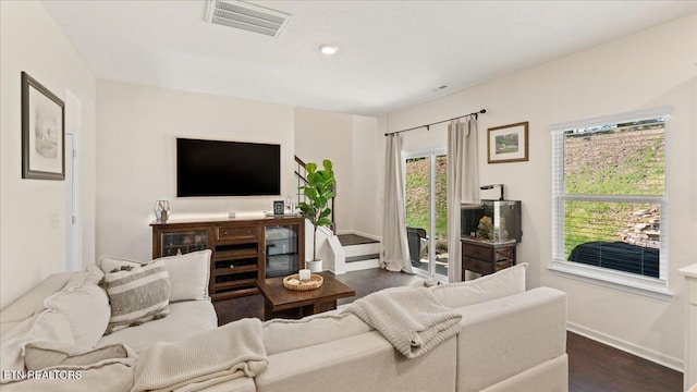 living room featuring recessed lighting, dark wood-type flooring, visible vents, and baseboards