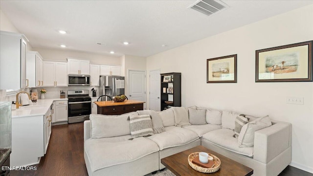 living room with dark wood finished floors, visible vents, and recessed lighting