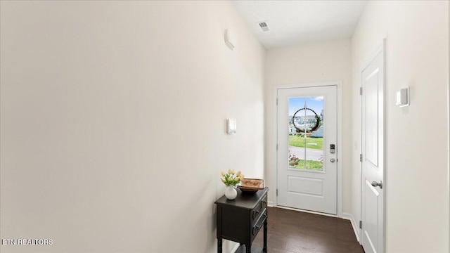 doorway to outside featuring dark wood-type flooring, visible vents, and baseboards